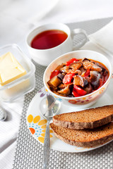 Vegetable sauté with eggplant, red pepper and tomatoes, and toasted rye bread on a plate