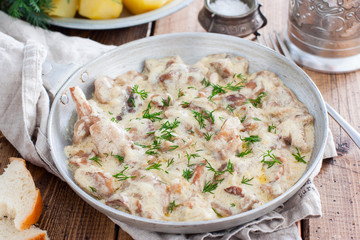 Forest mushrooms in sour cream sauce on a pan on a wooden table, horizontal