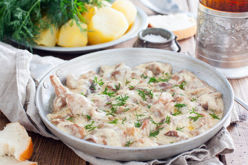 Forest mushrooms in sour cream sauce on a pan on a wooden table, horizontal