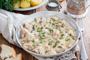 Forest mushrooms in sour cream sauce on a pan on a wooden table, horizontal