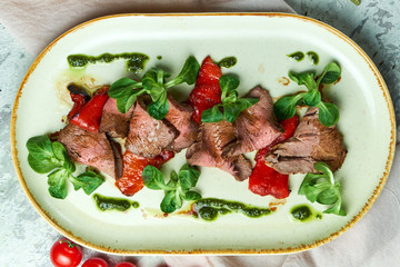 Carpaccio with sauce and spinach. Beautiful serving dishes. Light background. Restaurant menu