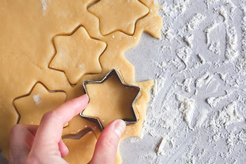 The process of baking cookies at home. The hand holds a form. Dough for cookies. Star-shaped cookies, pryanik. view from above