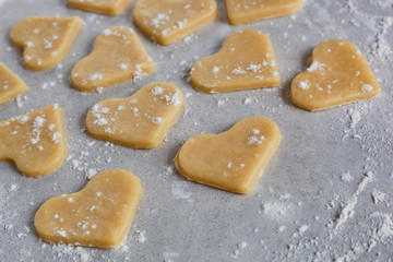 Raw dough cookies in the shape of hearts. The process of making cookies and gingerbread at home. 