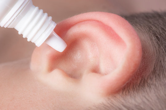 Medical Pipette With A Drop Of Medication Over The Patient's Ear