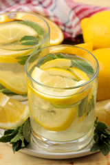 Homemade lemonade with mint and lemon in plastic glasses on a natural wooden background. Refreshing lemonade drink. close-up