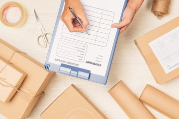 Courier hands writing on cardboard box at table