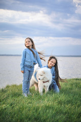 Sisters with a dog on the grass. Friendship concept.