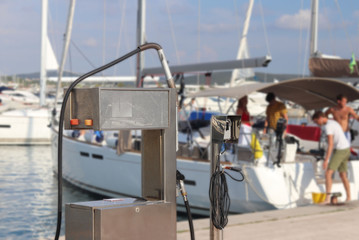 Fuel distributor on the pier of a gas station in the Mediterranean marina against the backdrop of sailing yachts. Refualing boats and fishing boats. Infrastructure of the Adriatic port. Saturday