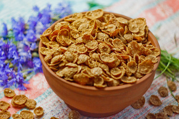 Sugarcorn flakes in a ceramic bowl closeup top view. light breakfast scattered on the table with blue flowers closeup. food fast cooking. healthy food, diet