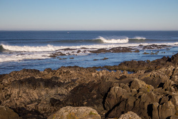 Waves crashing on rocks on Atlantic Ocean beach. Scenic seascape. Beautiful surf at seaside. Splashing waves with foam. Travel and vacation on shore. Rocky coastline. Nature power.