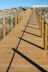 Wooden path with fence to the beach. Walkway on seashore in the morning. Travel and walk concept. Camino de Santiago landscape. Atlantic Ocean coast in Portugal. Wooden pier in perspective. 