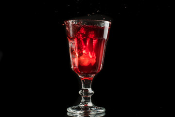 A glass of red wine on a white or black background with splashes.