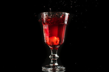 A glass of red wine on a white or black background with splashes.