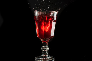 A glass of red wine on a white or black background with splashes.