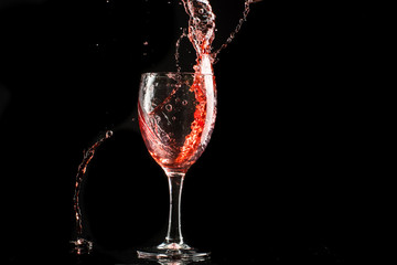 A glass of red wine on a white or black background with splashes.