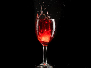 A glass of red wine on a white or black background with splashes.