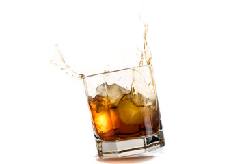 Fallen and falling whiskey glass with ice and splashes
