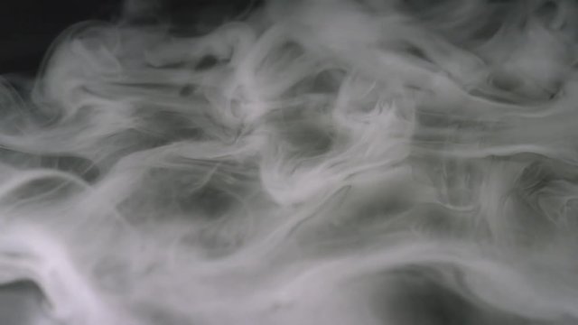 Close-up of puffs of white smoke floating in the dark. Stock footage. Isolated on black