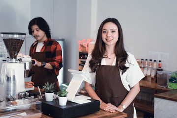 beautiful asian cafe owner smiling to camera in her coffee shop