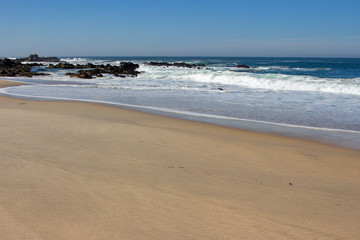 Waves crashing on rocks on Atlantic Ocean beach. Scenic seascape. Beautiful surf at seaside. Splashing waves with foam. Travel and vacation on shore. Rocky coastline. Nature power.
