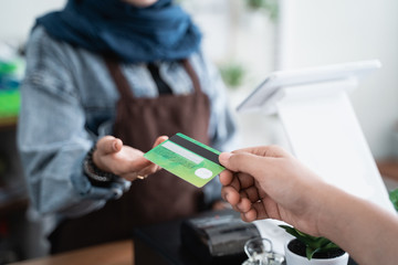 Obraz premium muslim cafe counter worker taking payment from customer with credit card