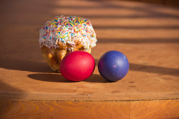 painted eggs and cake on a wooden table in Sunny color