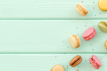 Brignt macarons for sweet break on mint green background top view mock up