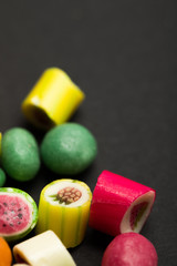 selective focus of delicious multicolored fruit caramel candies on black background
