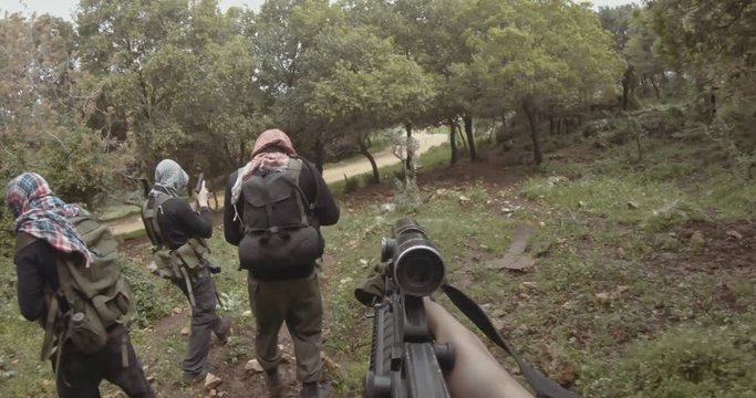 POV footage of armed terrorists patrolling a forest area