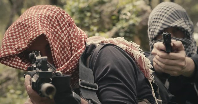 Squad of armed terrorists patrolling a forest area during combat
