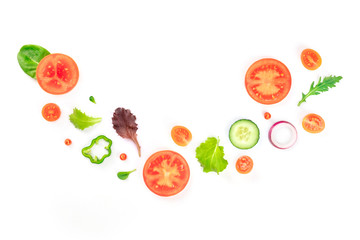 Fresh vegan vegetable salad ingredients, shot from the top on a white background. A flat lay composition with organic tomato, cucumber, peppers, onion slices and mezclun leaves