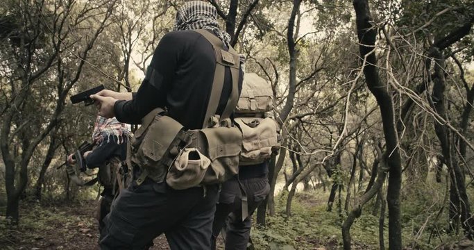 Squad of armed terrorists patrolling a forest area during combat