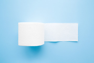 Soft, white toilet paper roll on light pastel blue background. Hygiene concept. Empty place for text or logo. 