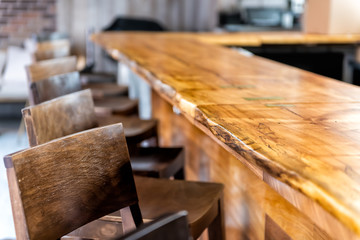 Row of empty wooden vintage bar stools by counter in drink establishment pub during day closeup of retro wood and nobody - obrazy, fototapety, plakaty