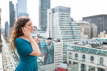 Young woman standing on rooftop restaurant in New York City NYC at wedding reception thinking looking at cityscape skyscrapers
