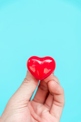 One hand holding red heart shaped ceramic for love concept.