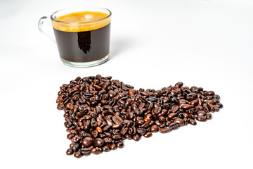 Side view of black coffee in clear glass cup  with dark roasted coffee bean form in heart shape and wood on white background. I love coffee concept