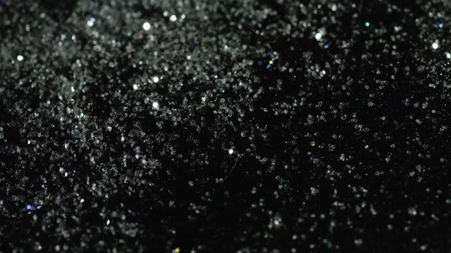Close-up of sparkling glass particles on the black background. Stock footage. White and black concept
