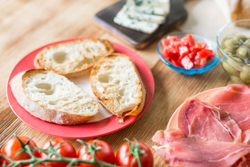 Toasted ciabatta slices and ingredients for making bruschetta on a wooden background.