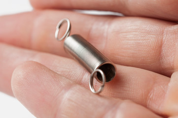 Metal spring in hand isolated on white background