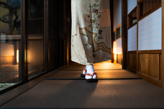 Traditional japanese house or ryokan with tatami mat floor and shoji sliding paper doors and woman in kimono and geta shoes tabi socks walking