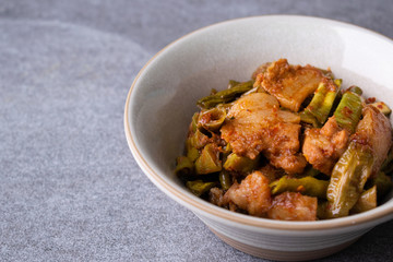 Spicy fried three layer pork with lentils in gray bowl on the concrete table background.