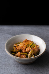 Spicy fried three layer pork with lentils in gray bowl on the concrete table background.