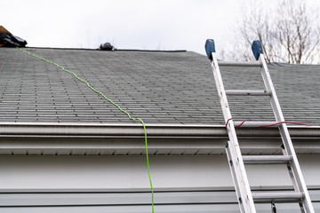 Front closeup of house during day over garage with gray color Single Family Home and roof shingles and ladder during repair © Andriy Blokhin