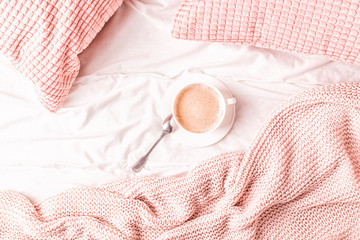 Bed with pink knitted plaid and coffee