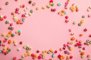 Fototapeta na wymiar top view of multicolored candies scattered on pink background with copy space