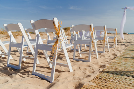 Wedding chairs decorated with star fish and straw,on a sand beach for wedding ceremony