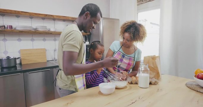 Black parents and daughter in kitchen making dough