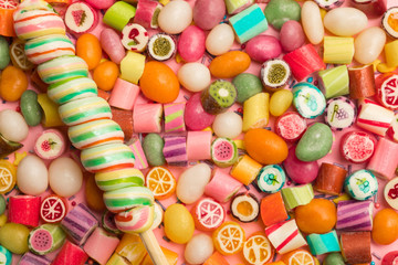 top view of bright delicious multicolored caramel candies and swirl lollipop on wooden stick