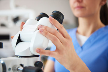 Close up of dentist's hands holding dental microscope